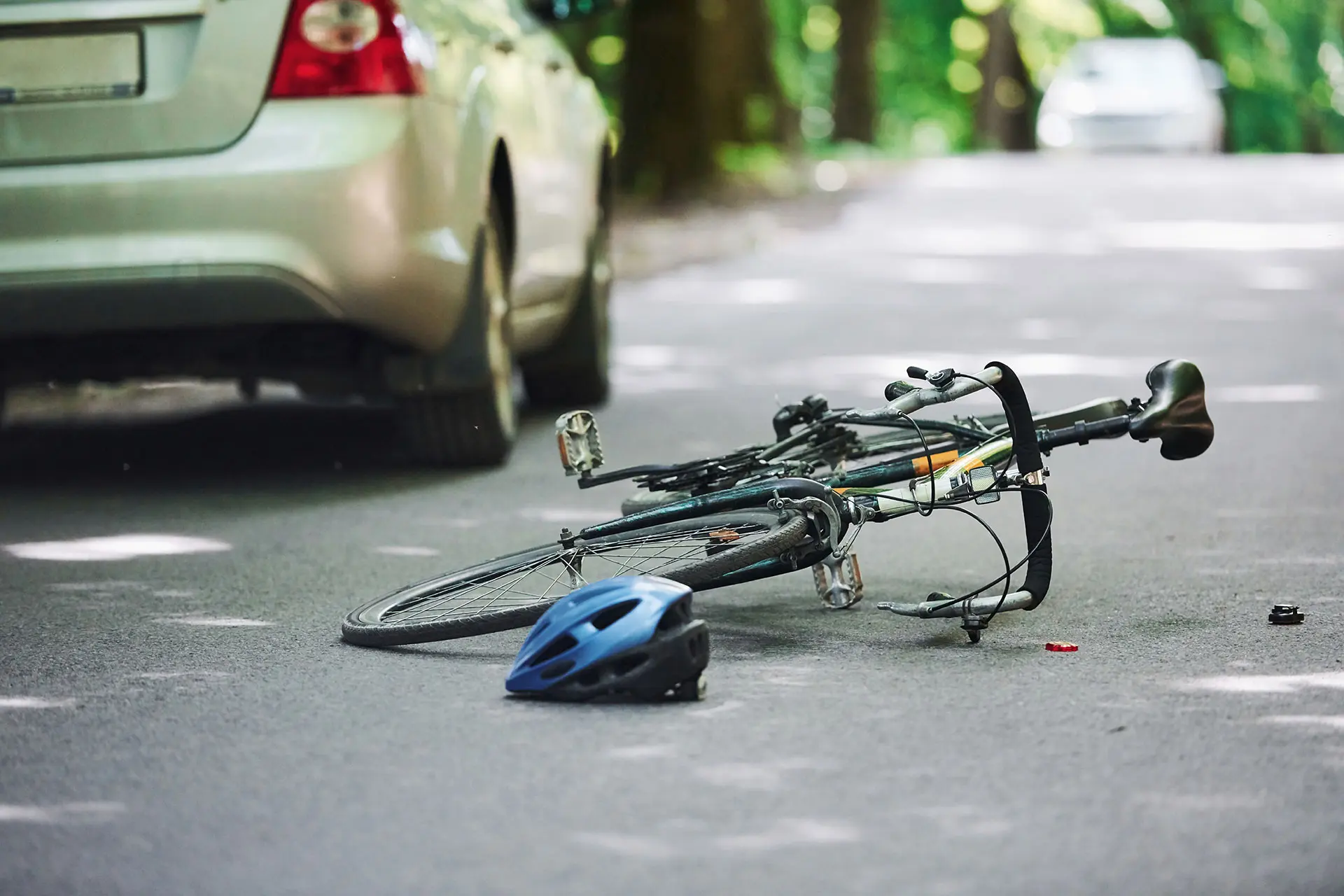 Bicycle and silver colored car accident on the road at forest at daytime