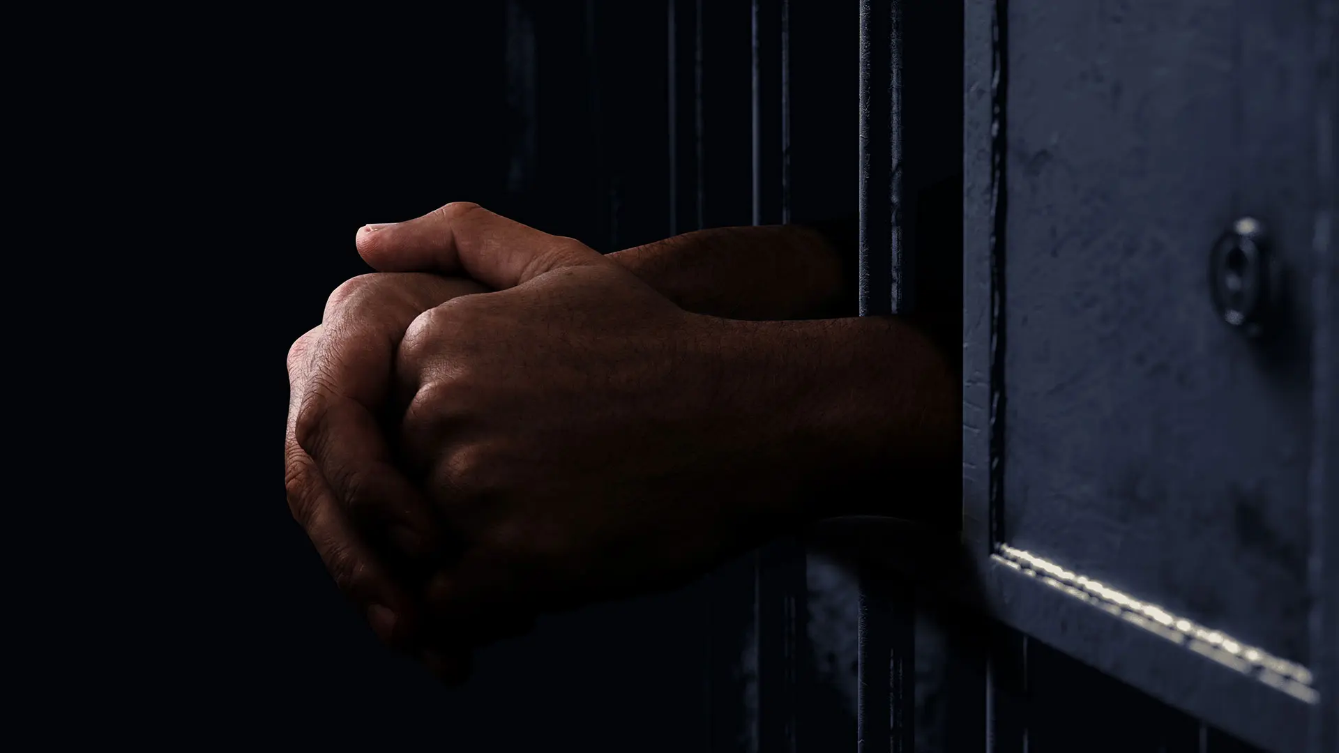 Hands hanging out of a jail cell