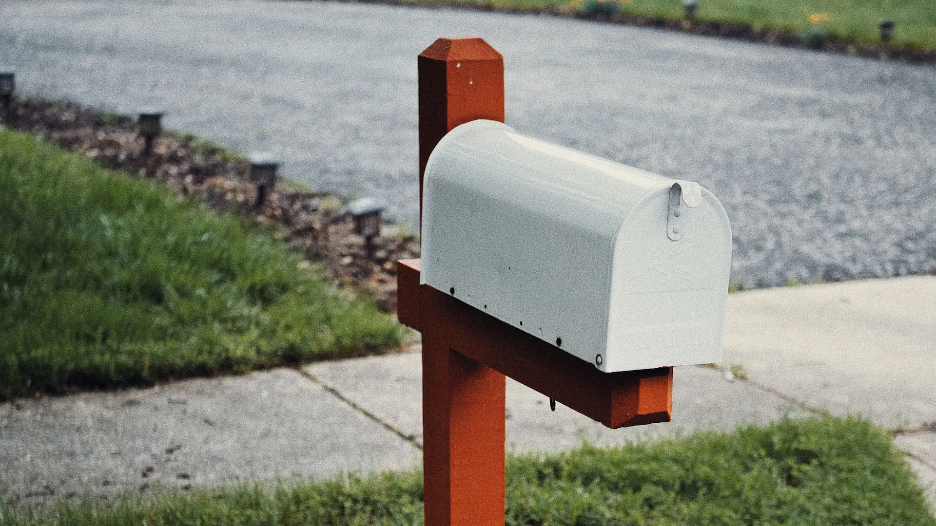 White metal mail box in front of house and yard