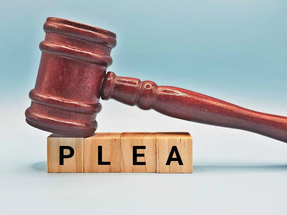 Judge’s gavel resting on wooden blocks spelling the word plea, symbolizing plea bargain or court decision. Judge’s gavel resting on wooden blocks spelling the word plea, symbolizing plea bargain or court decision.
