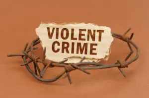  On a brown surface, barbed wire and a cardboard sign with the inscription - Violent crime