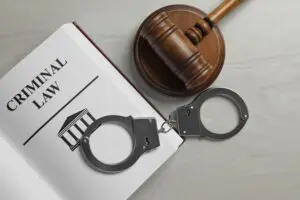 Judge's gavel, handcuffs and Criminal law book on white wooden background, 