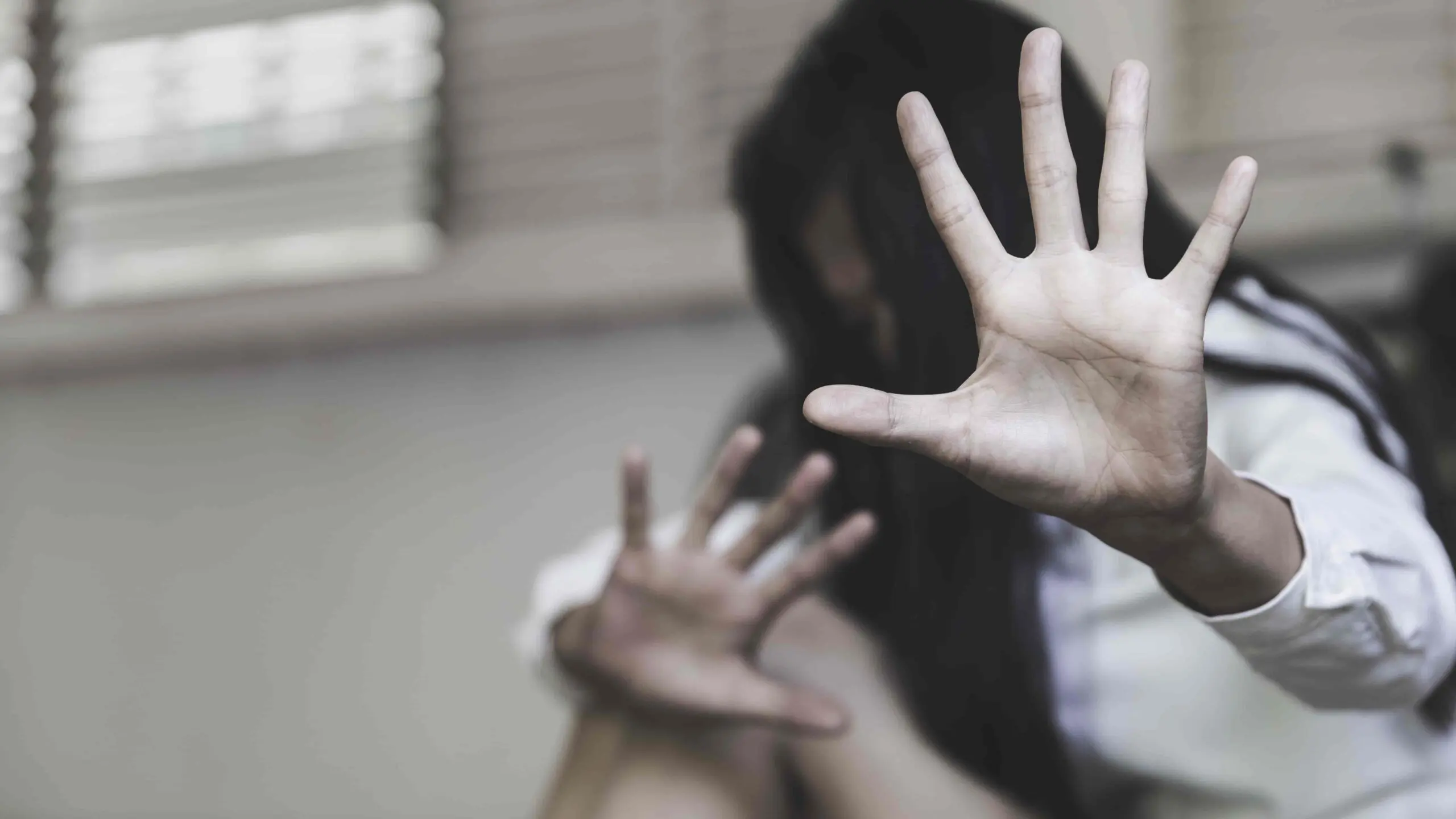 Terrified woman raising hands in self-defense, concept of abuse and victim protection.