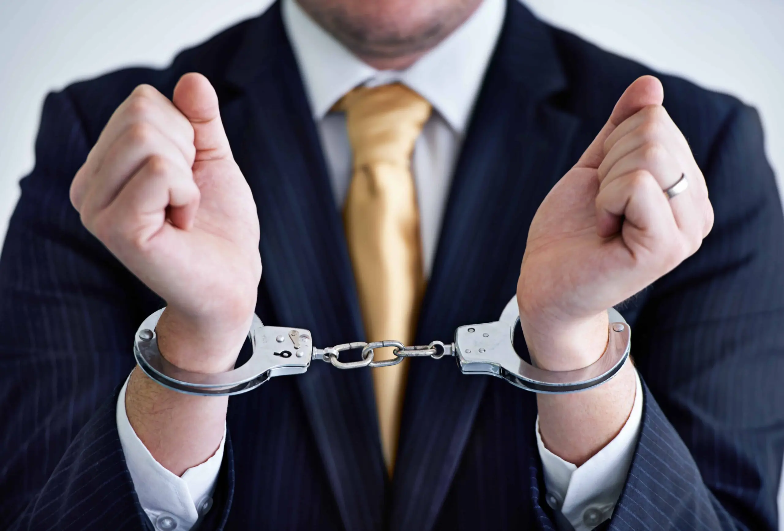 Businessman in handcuffs wearing suit and tie symbolizing white-collar crime or corporate arrest.