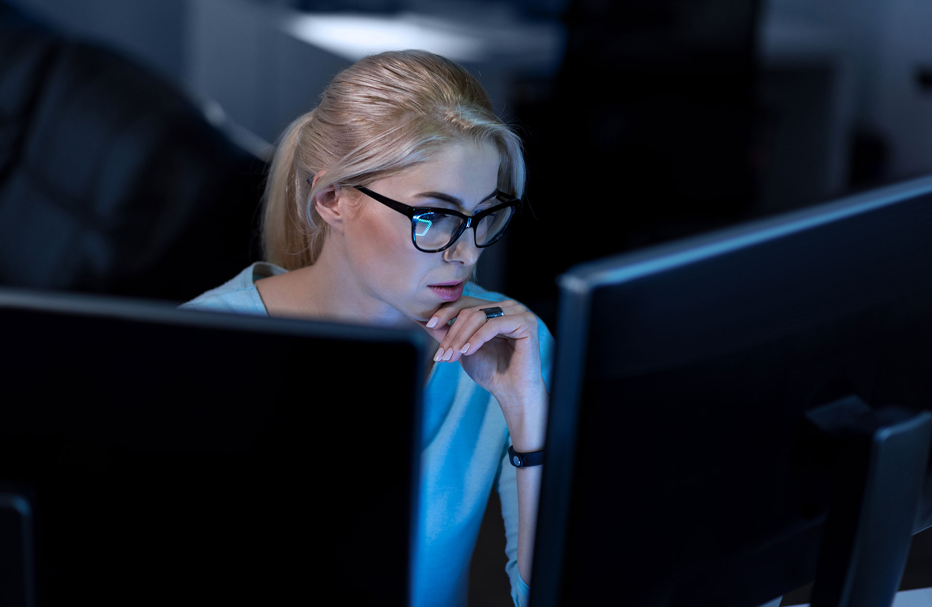 Female hacker in front of computers in dark room