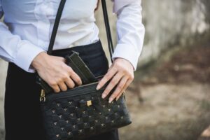 Woman conceal carry weapon hand holding removing small handgun from her purse for self defense